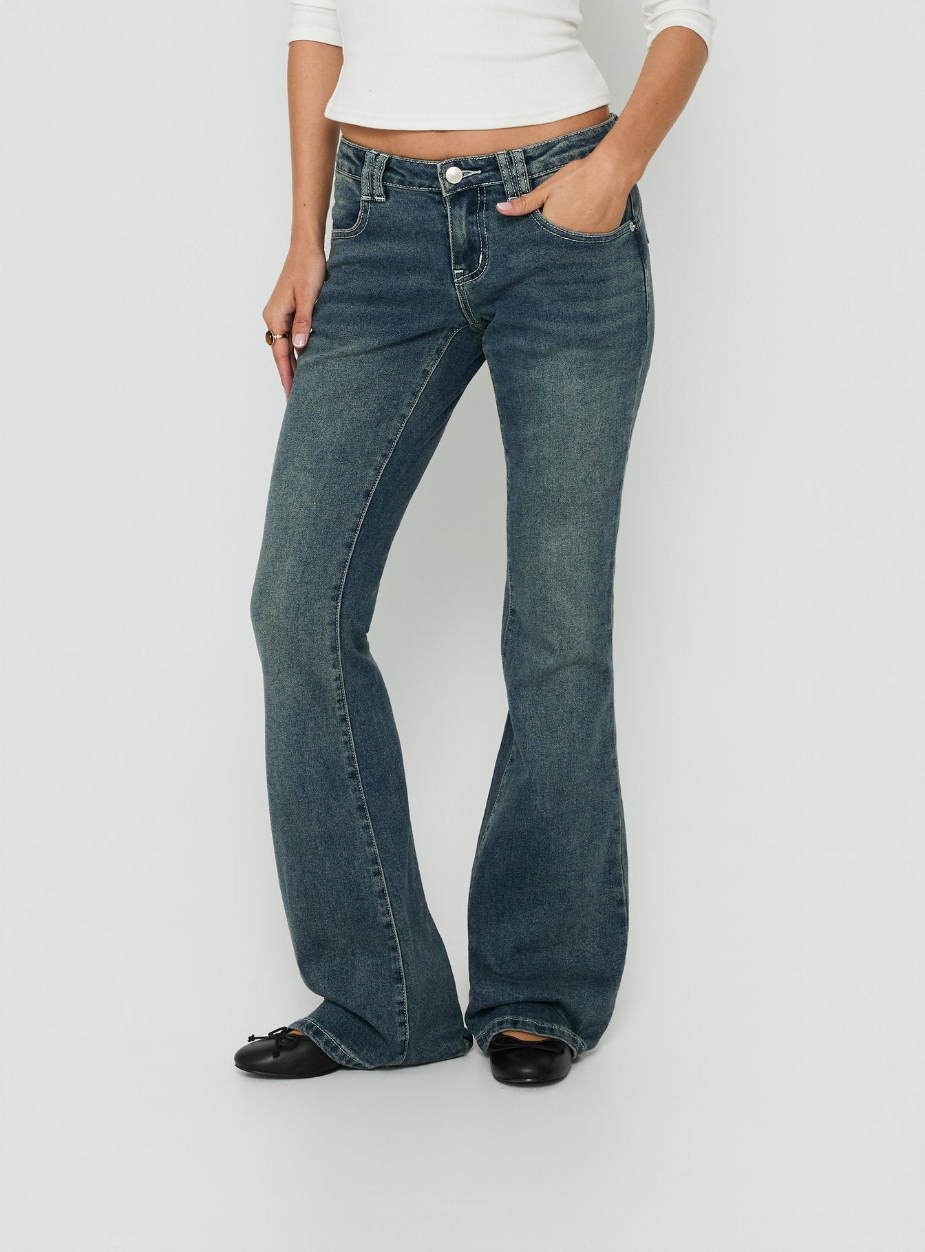 A detailed look at Clynee Ultra Low Rise Bootleg Jeans Dirty Blue womens-jeans with low-rise waist side view of model wearing Princess Polly