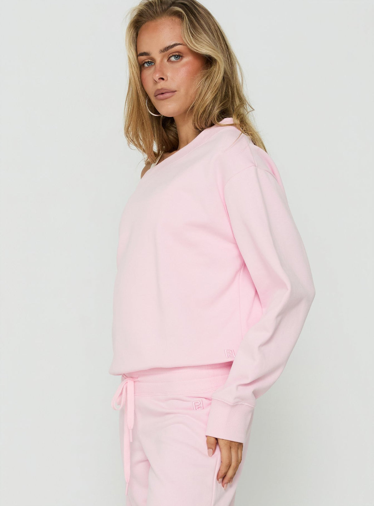 Explore the Wellness Off The Shoulder Jumper Pink womens-jumpers with short length side view of model wearing Princess Polly