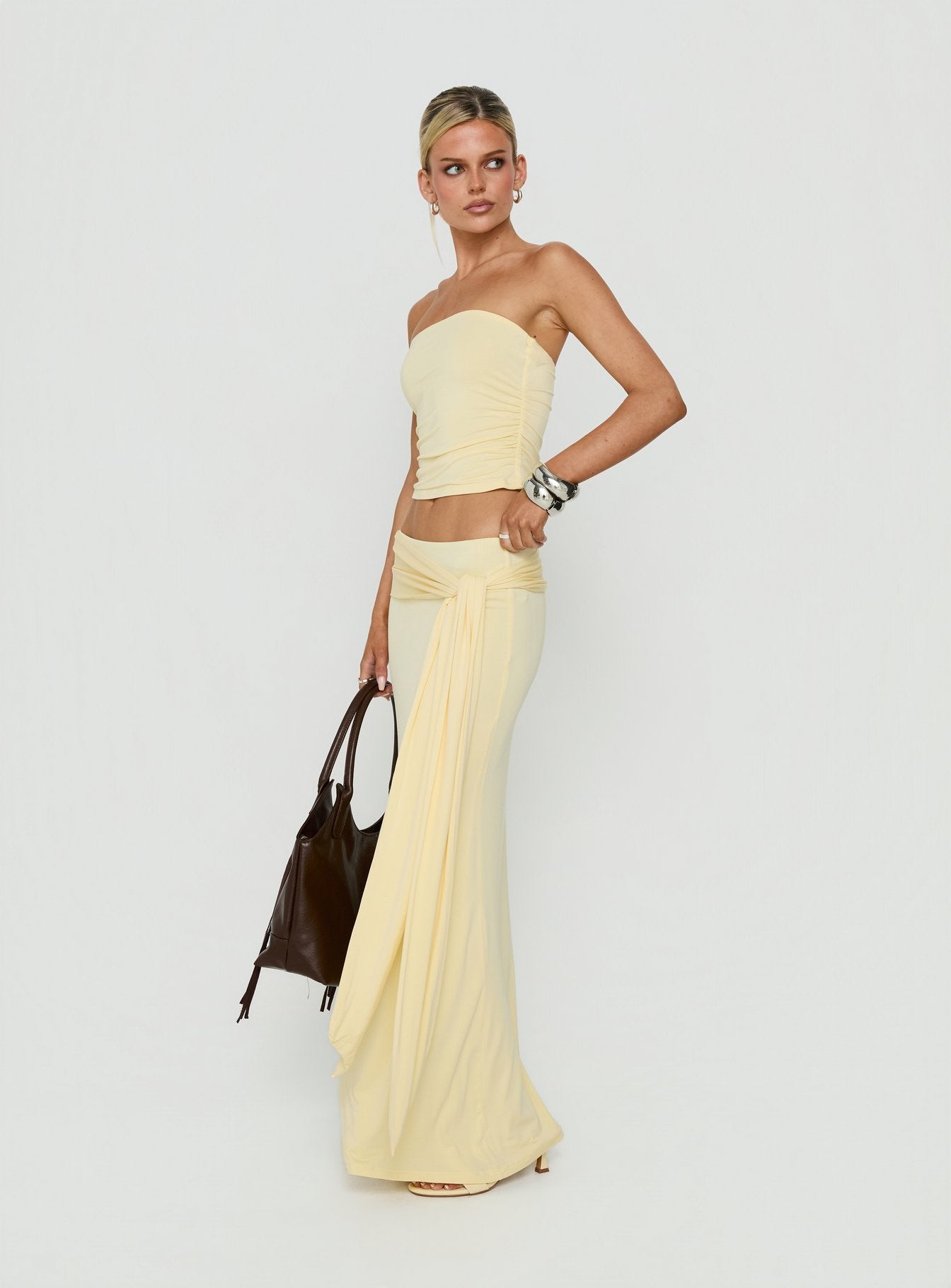 Presenting the Aymee Tie Detail Maxi Skirt in Yellow, a women's skirt with relaxed fit, lace hem, solid print, aline shape, and wrap details side view of model wearing Princess Polly