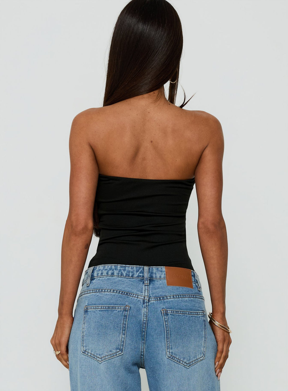 Designed with the Namari Strapless Bodysuit Black womens-bodysuit in sleeveless ruched style back view of model wearing Princess Polly