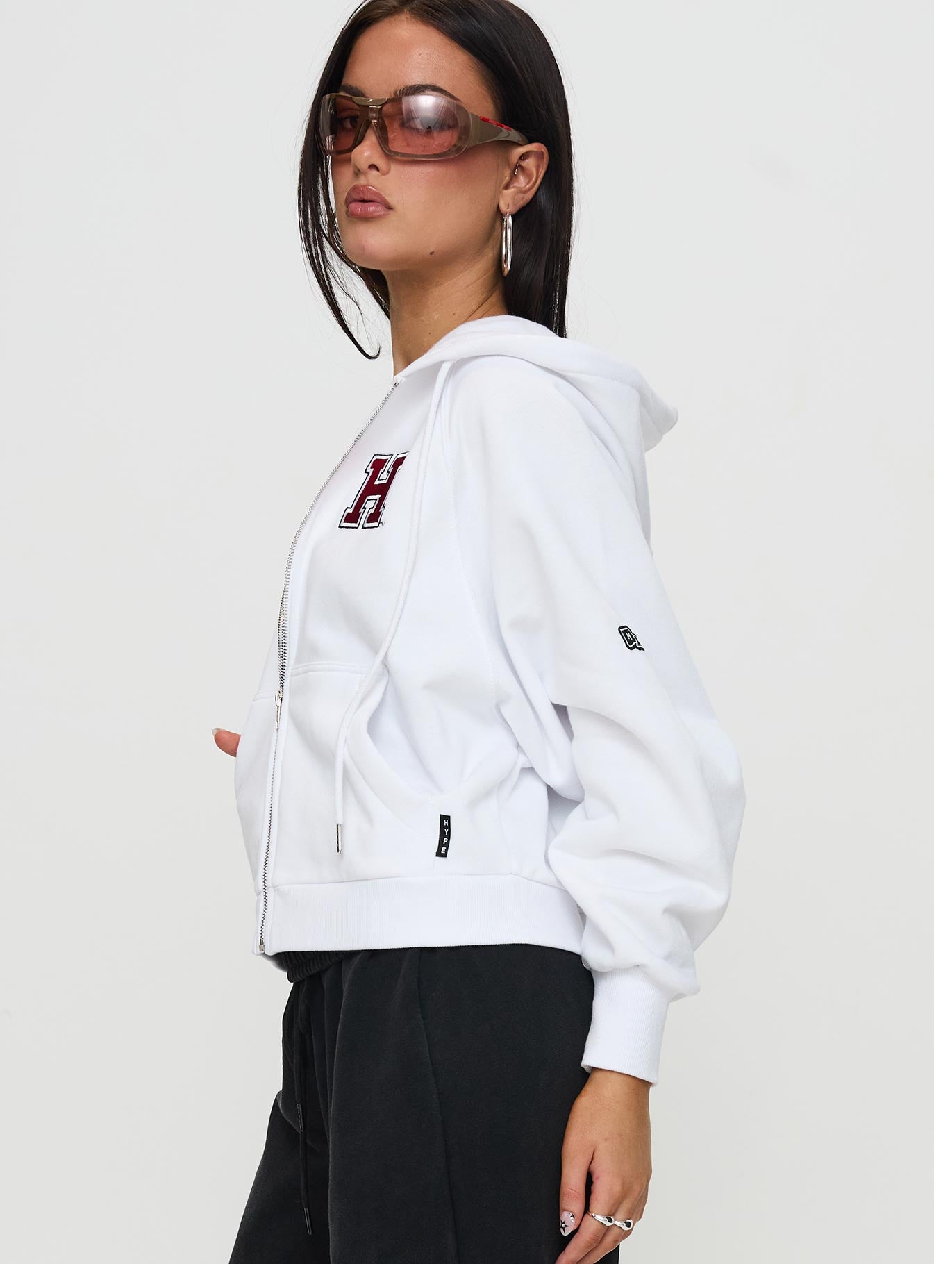 side view of model wearing Princess Polly Harvard Raglan Zip Up White / Red Jumpers 
