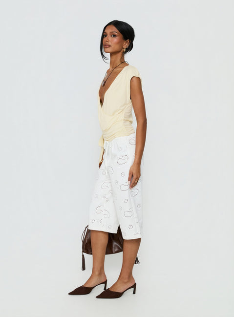 side view of model wearing Princess Polly Roda Anglaise Longline Shorts White Mid Rise Pants 