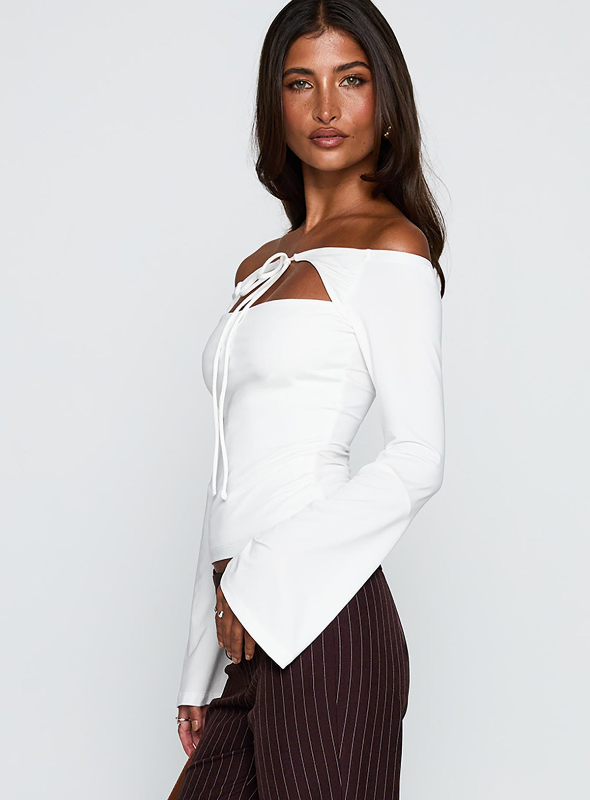 side view of model wearing Princess Polly Nevah Long Sleeve Top White Full Sleeves straight 