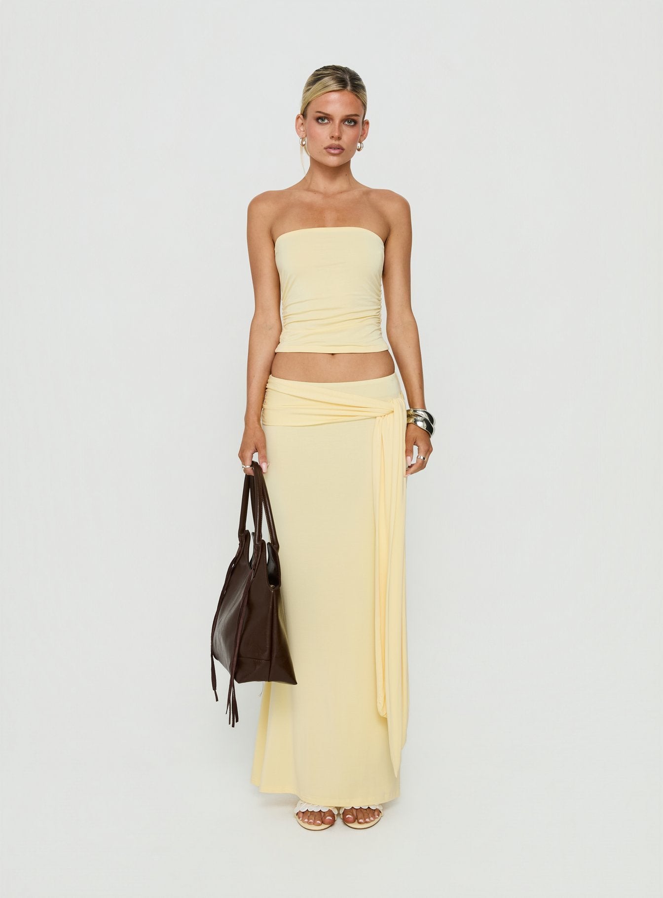Showcasing the Aymee Tie Detail Maxi Skirt in Yellow, a women's skirt with relaxed fit, lace hem, solid print, aline shape, and wrap details front view of model wearing Princess Polly