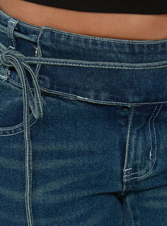 Crafted from Runa Low Rise Tie Side Jeans Mid Blue Wash featuring womens-jeans with flared wide-leg silhouette Princess Polly