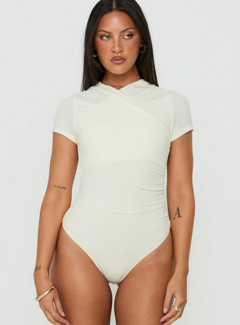 Discover the Odettea Cross Front Short Sleeve Bodysuit in Cream womens-bodysuit with short sleeves front view of model wearing Princess Polly